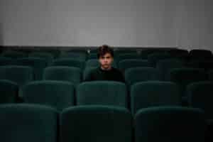 boy in blue shirt sitting in empty theater